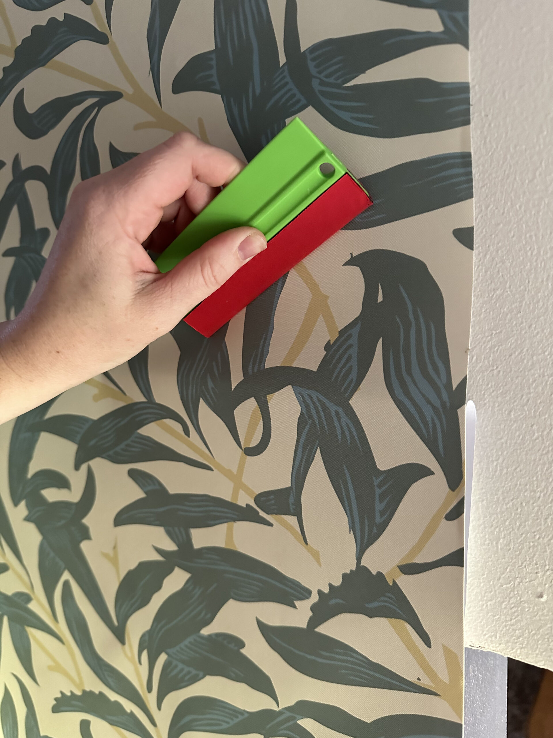 using a smoothing tool to smooth wallpaper