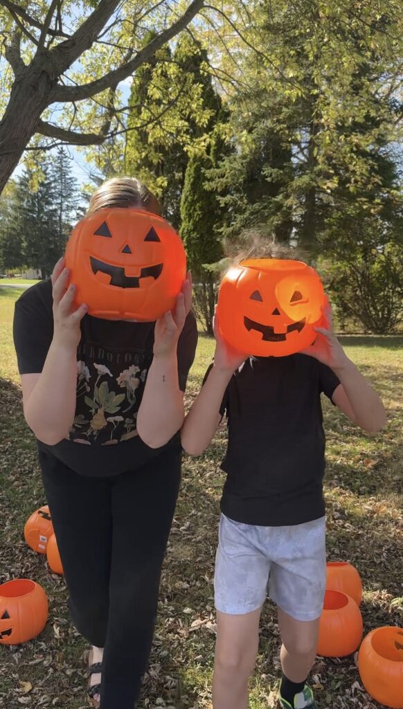 two people holding trick or treat pumpkin buckets in front of their faces