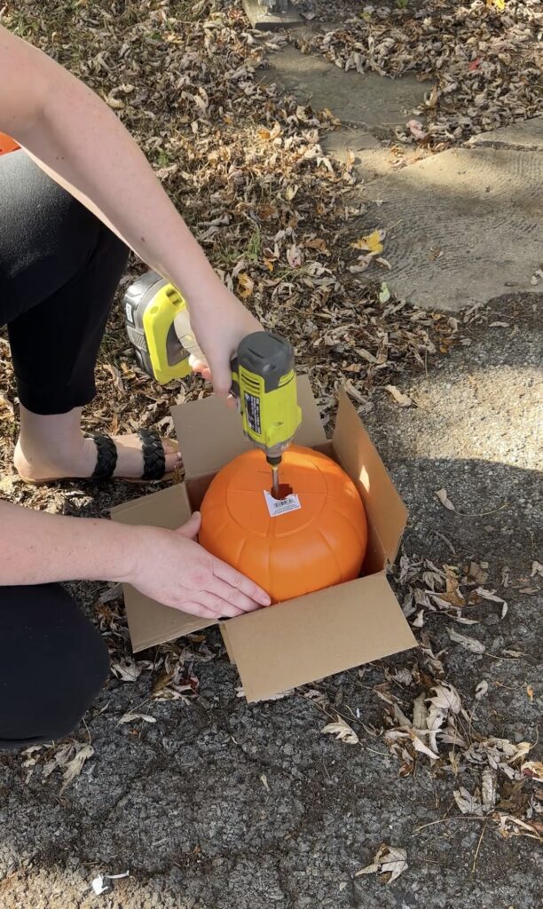 using a spade drill bit to make a hole in the bottom of pumpkin bucket for rain drainage