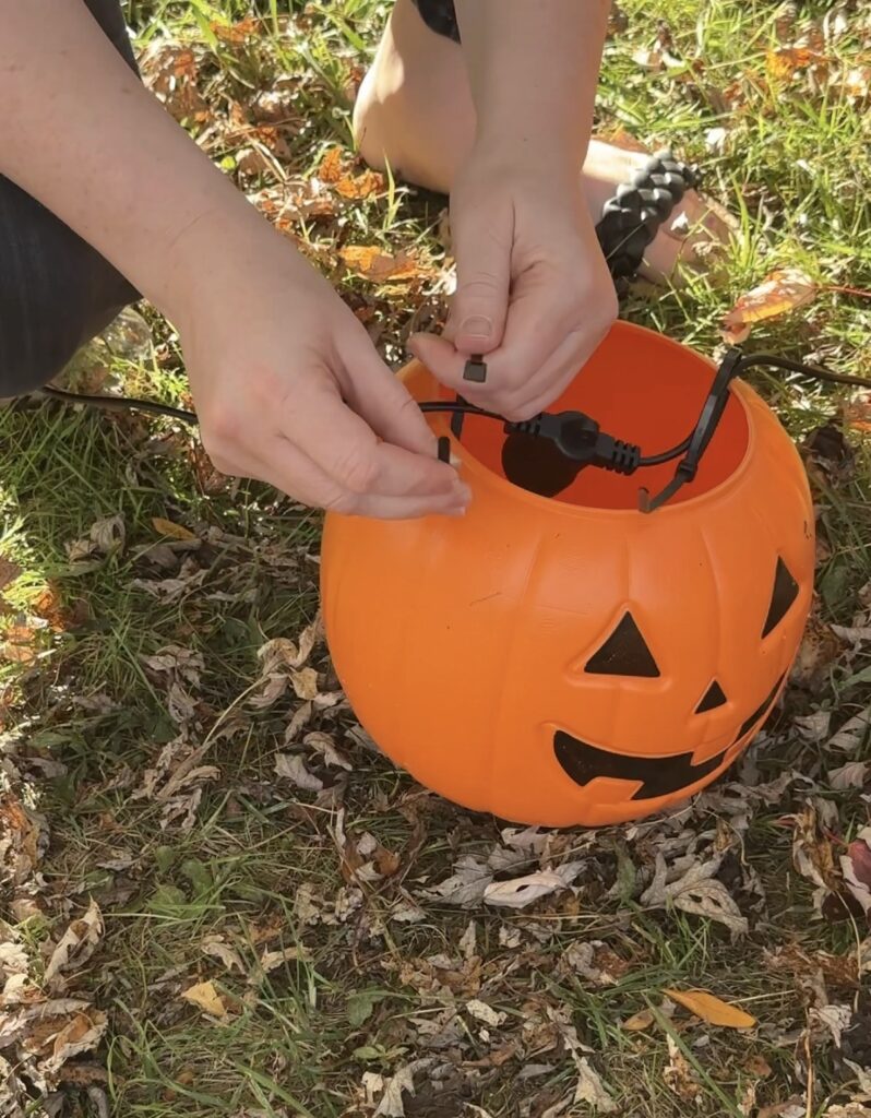 attaching string lights to pumpkin bucket with zip tie